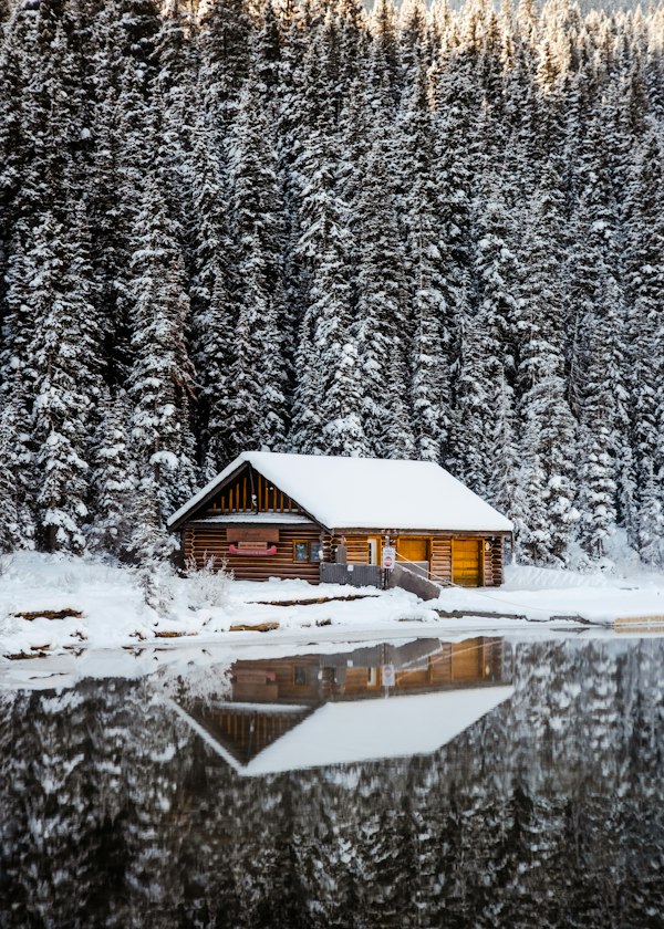 A cabin on a frozen lake surrounded by snow-covered trees in winter