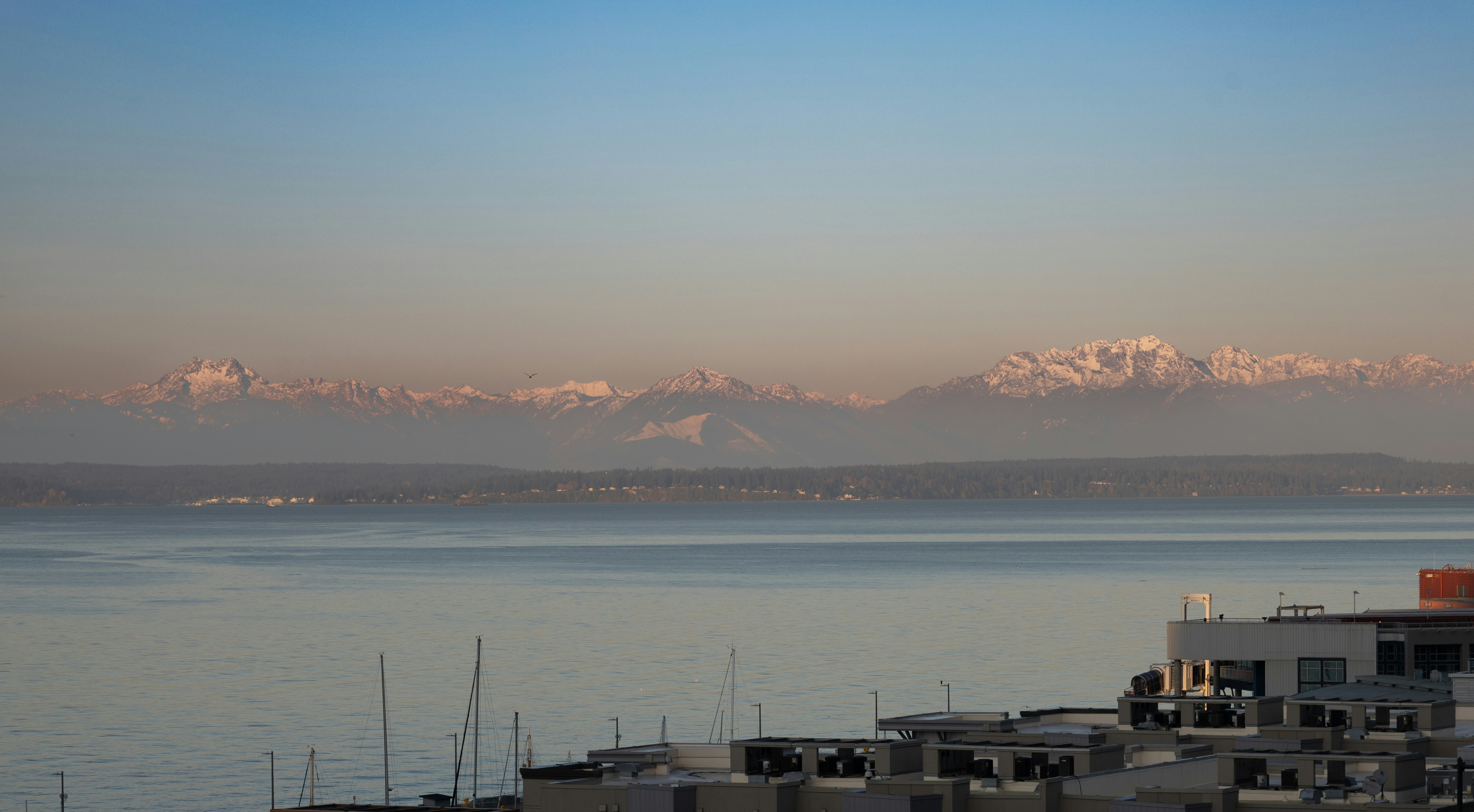 a body of water with buildings and mountains in the background