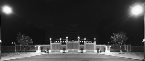 Nighttime view of a beautifully lit electric gate guarding a garden house.