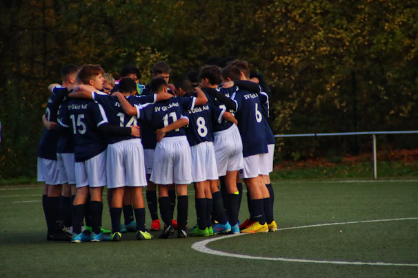 A vibrant team huddle of young flag football players in Potros Occidente uniforms celebrating a great play.