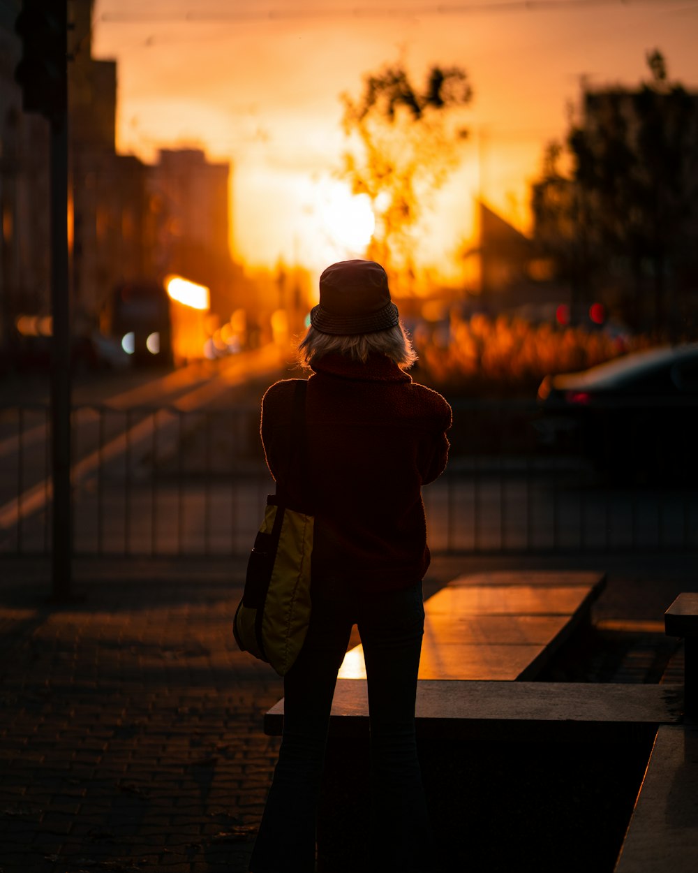 a person standing on a sidewalk with a fire in the background