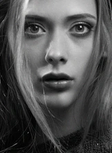 A powerful close-up black-and-white portrait of a focused MMA fighter in the cage under dramatic lighting.