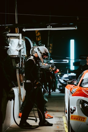 Pit stop moment with blurred mechanics in red lighting, emphasizing speed and intensity.