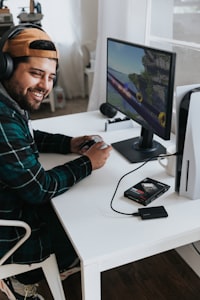 a man wearing headphones and sitting at a desk with a computer