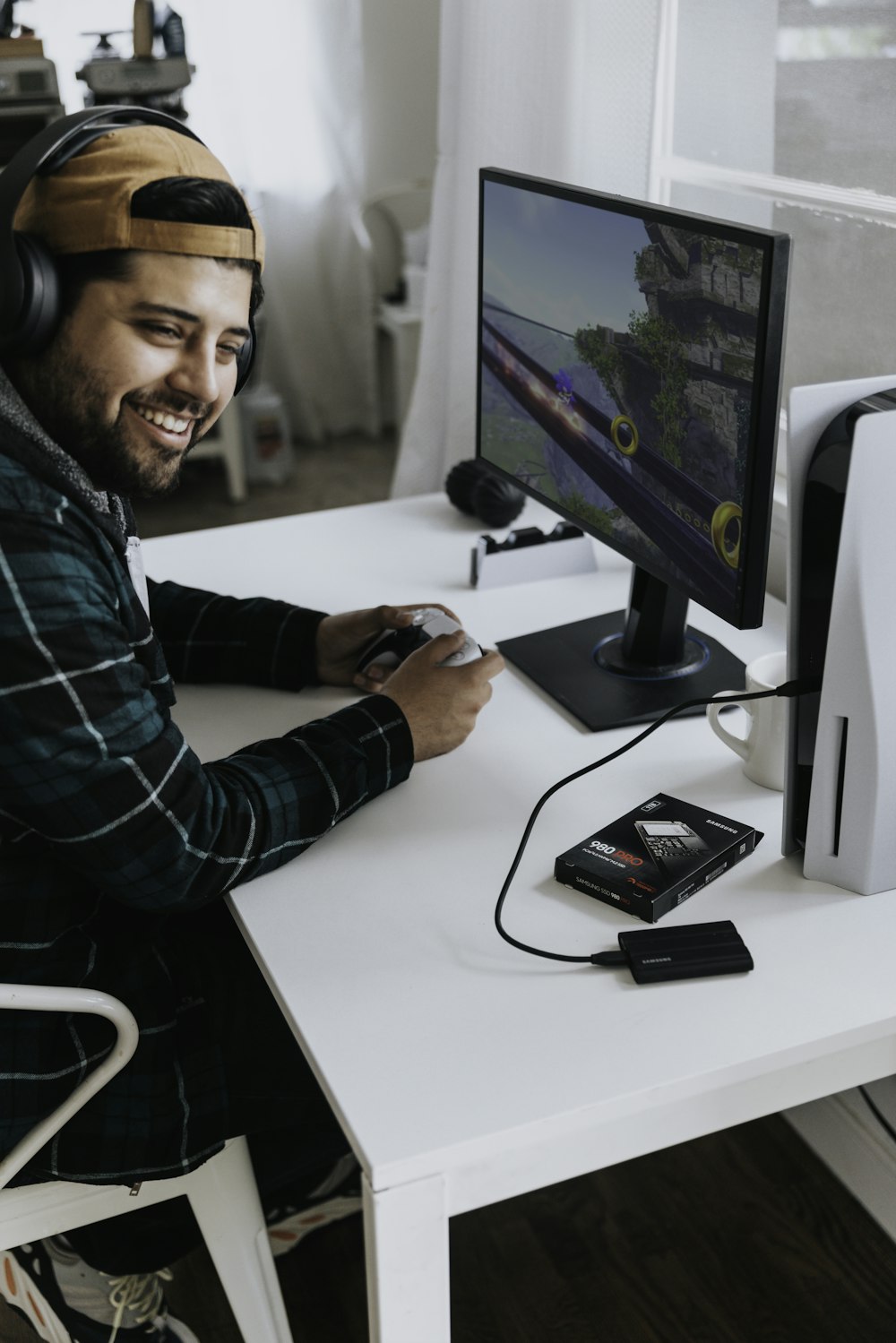 Ein Mann mit Kopfhörern sitzt an einem Schreibtisch mit einem Computer