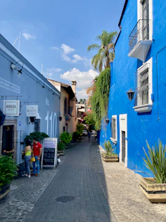 a couple of people walking down a street between buildings