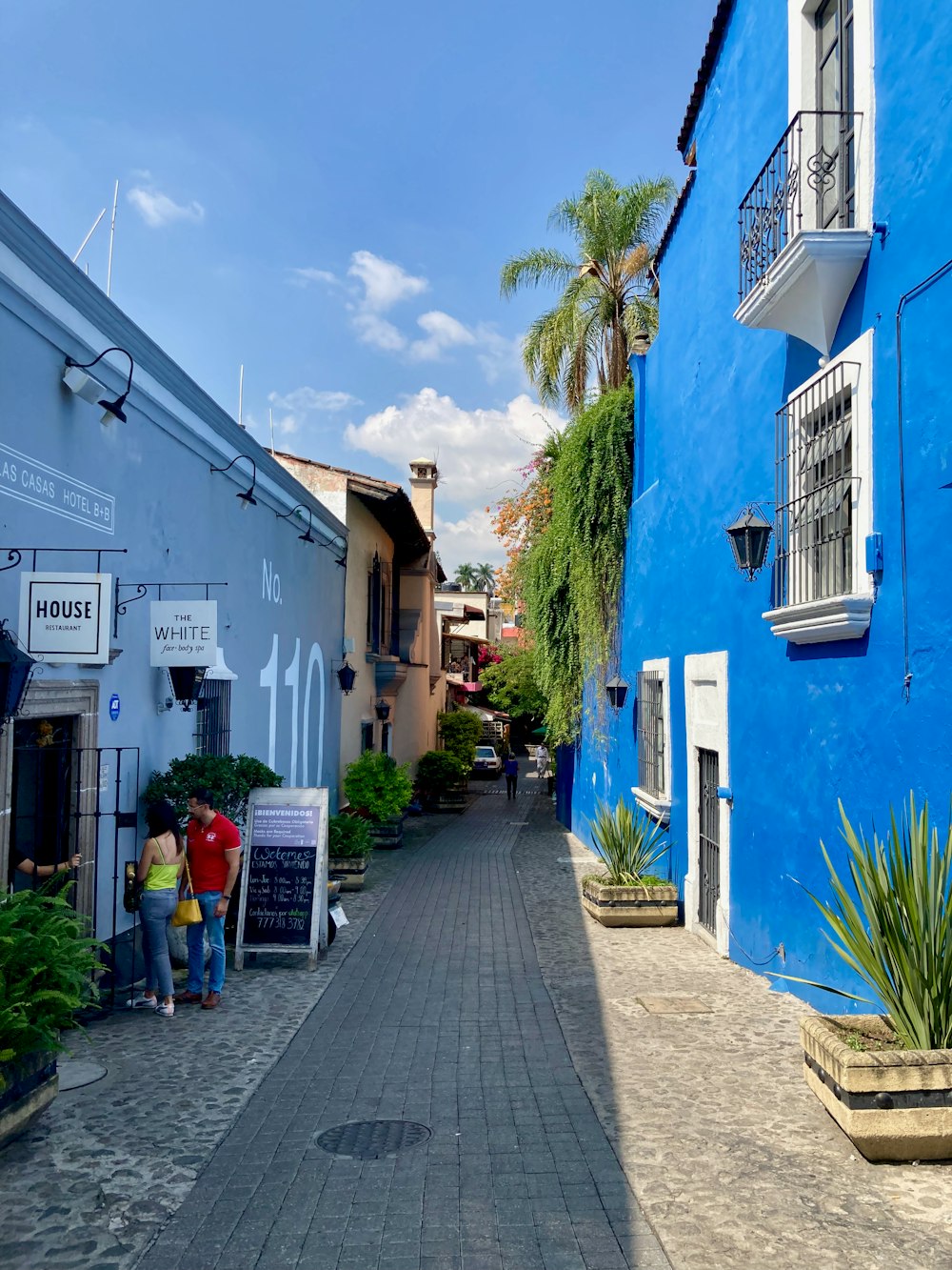 a couple of people walking down a street between buildings