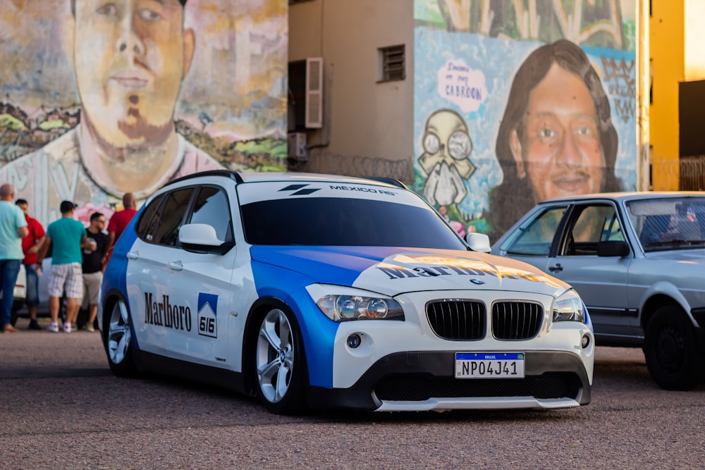 Un coche azul aparcado frente a una pared con arte