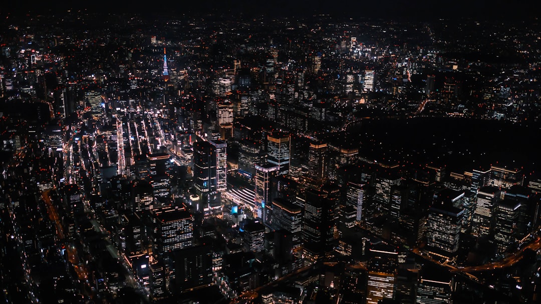 a city at night, Above Tokyo in a helicopter with Tokyo Tower in the distance and Tokyo station below at night time
