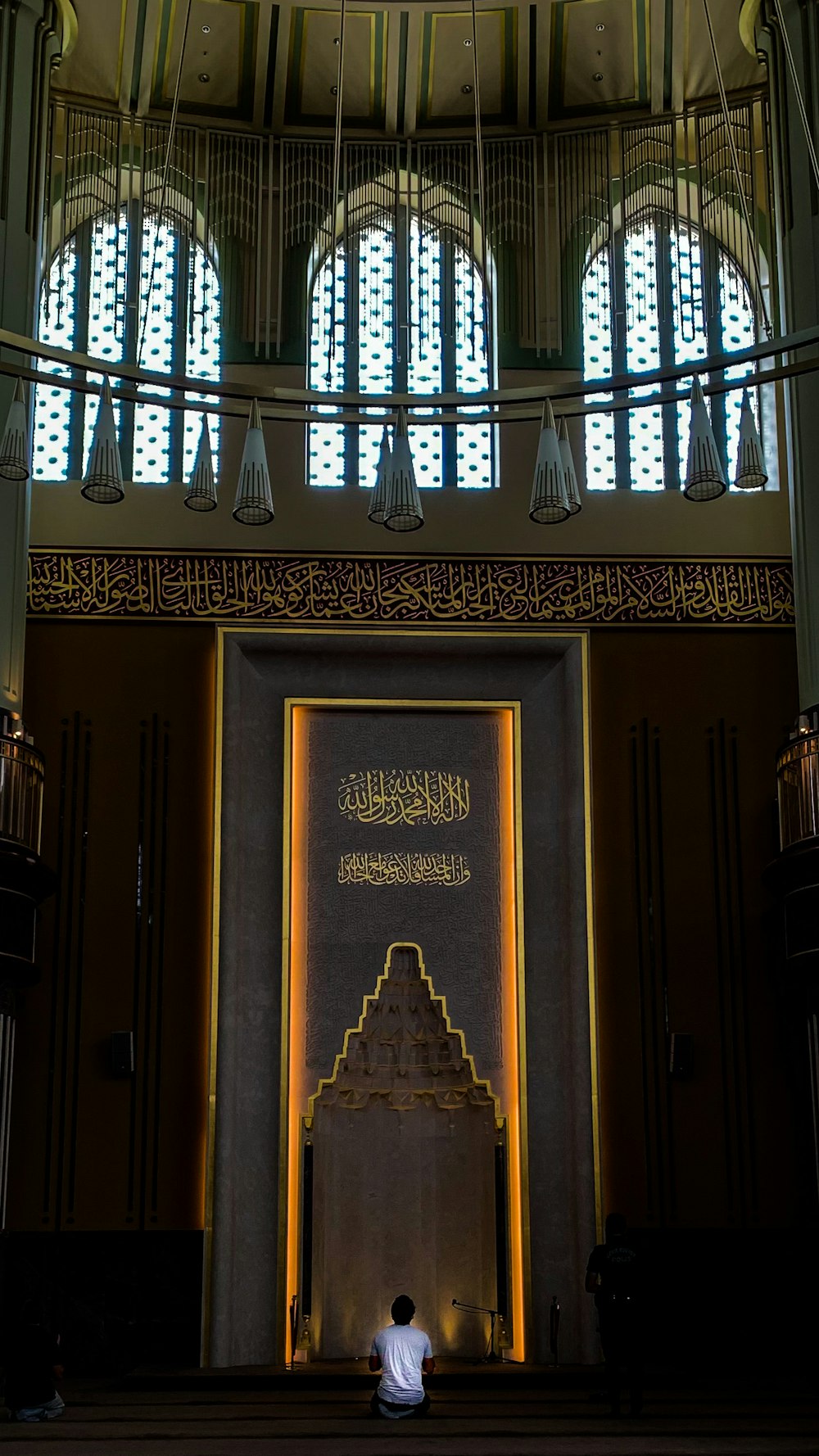 a person sitting in a room with a large gold door and chandelier