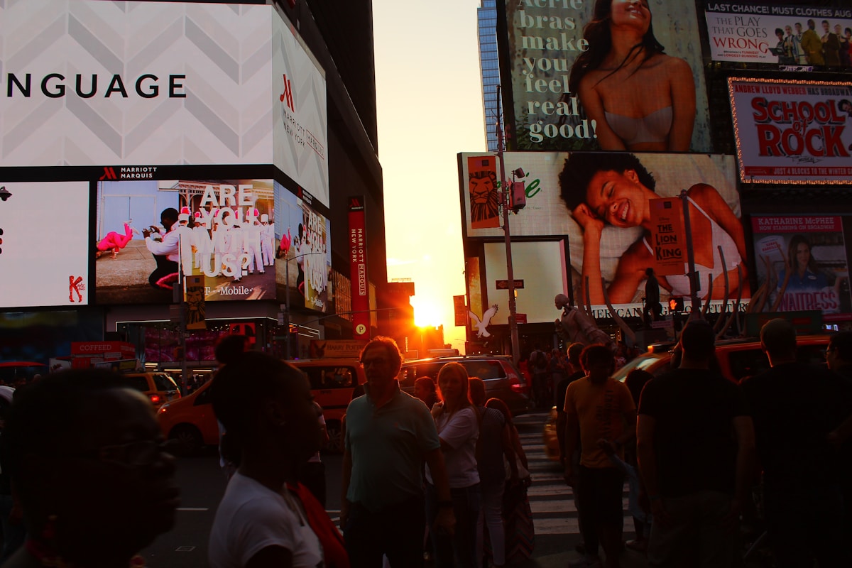 A crowd of people walking on a street with large billboards