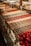 A display case filled with a variety of colorful and neatly arranged pastries or sweets. Each row features different types of confections, including chocolates and round, red truffles. The background includes trays of more pastries, showcasing a rich assortment of treats.