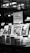 A black and white image features a bookstore shelf labeled 'History & Current Events', showcasing a selection of books. Notable titles include works about Anne Frank, the Battle of the Atlantic, and Auschwitz. The background is out of focus, creating a serene environment typical of a bookstore.