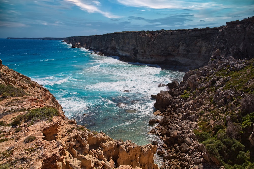 a rocky cliff with a body of water below