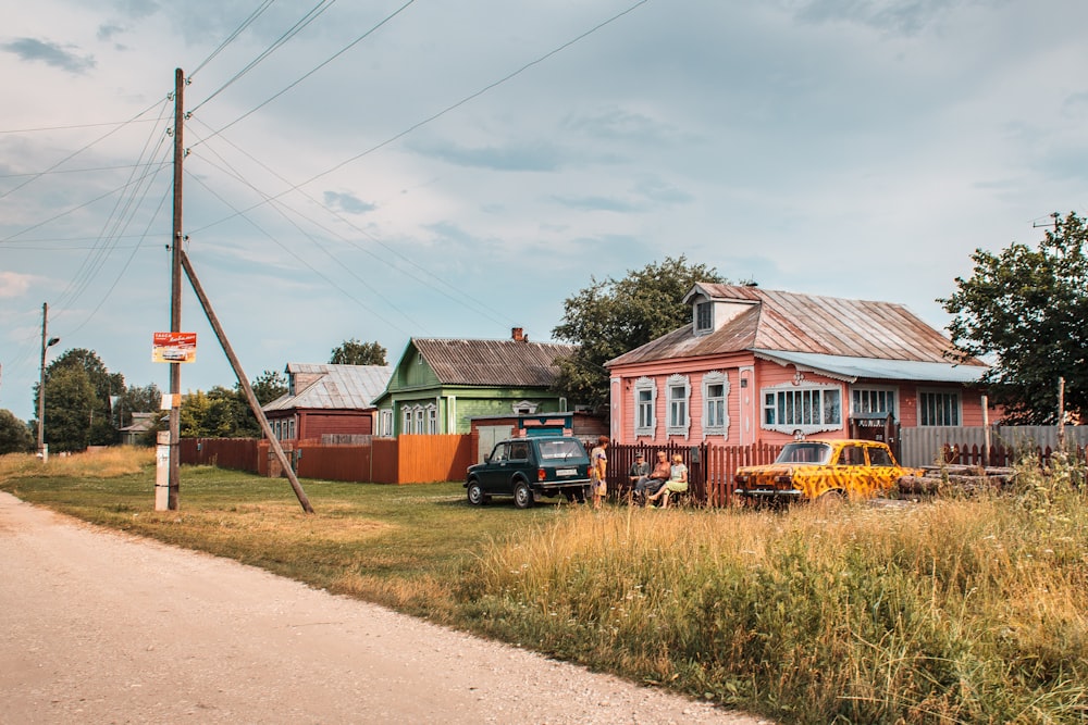 a road with cars parked on the side and a house in the background