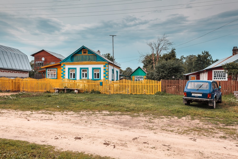 a blue truck parked in front of a yellow house