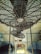 Three ceiling fans are mounted inside a train compartment, showcasing metal grilles and aging infrastructure. The compartment has a worn and industrial look, with a small window and seating area visible below.