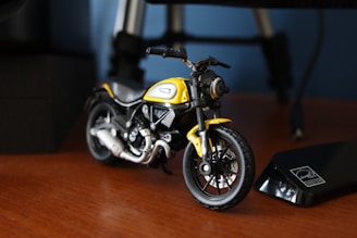 A detailed close-up of a miniature motorcycle model displayed on a wooden shelf.