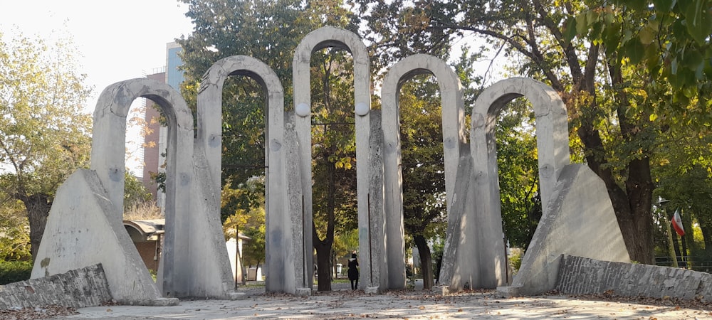 une personne debout devant une grande arche de pierre