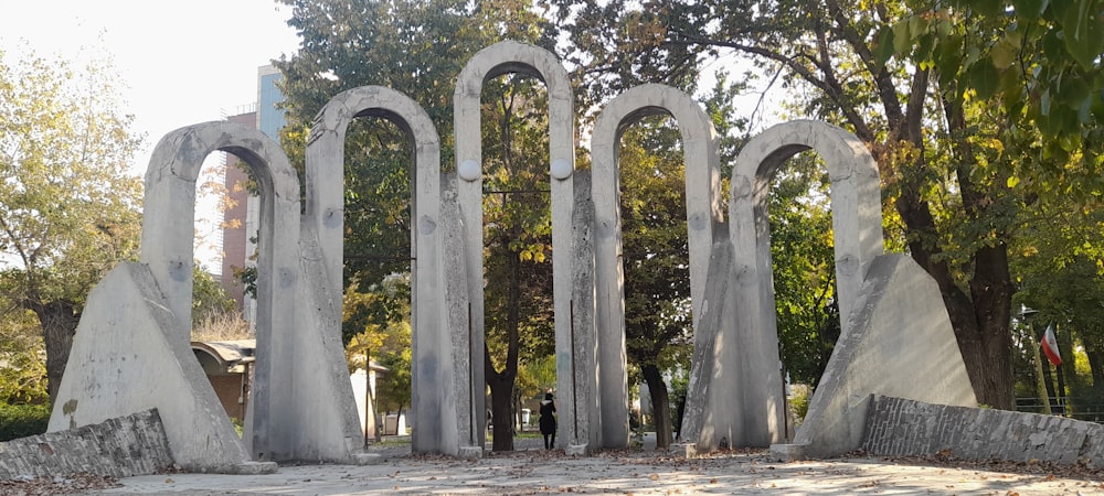 Una persona parada frente a un gran arco de piedra