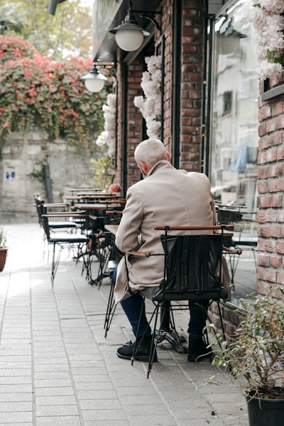 A man sitting alone at an outdoor table, lost in thought