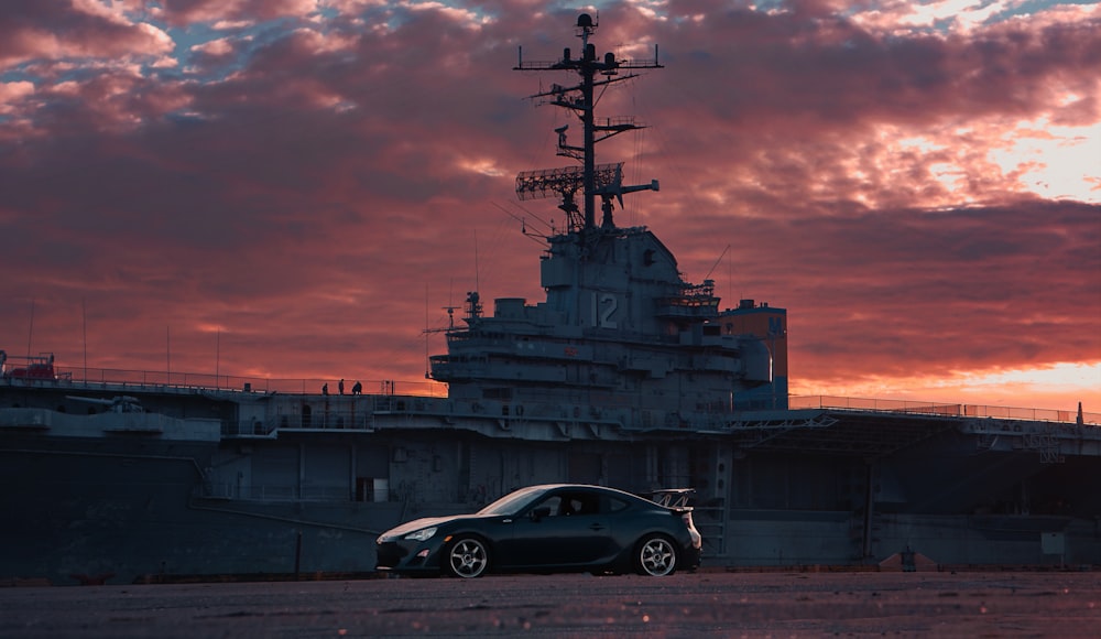 a car parked in front of a large ship