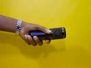 Close-up of hands holding a microphone with an orange wristband visible.