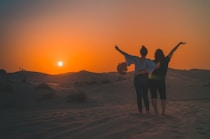 a group of people standing on a hill with the sun setting