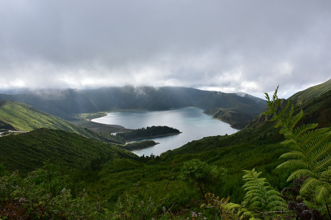 a body of water surrounded by hills, `Clouds over the volcanic lake`