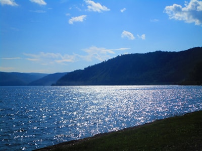 A serene lakeside view with gentle ripples reflecting a muted blue sky.