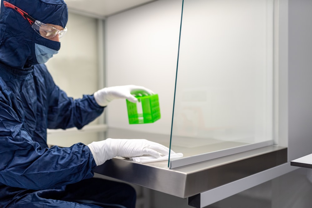 a person in a lab coat holding a green container