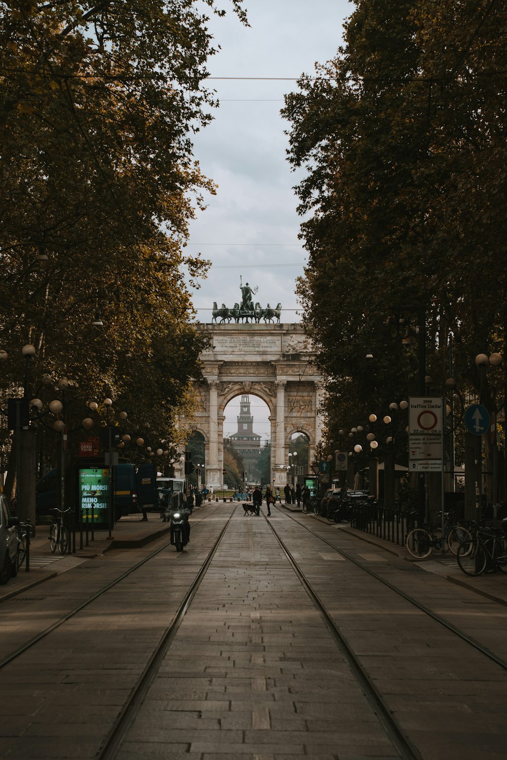 a stone archway with trees and bicycles