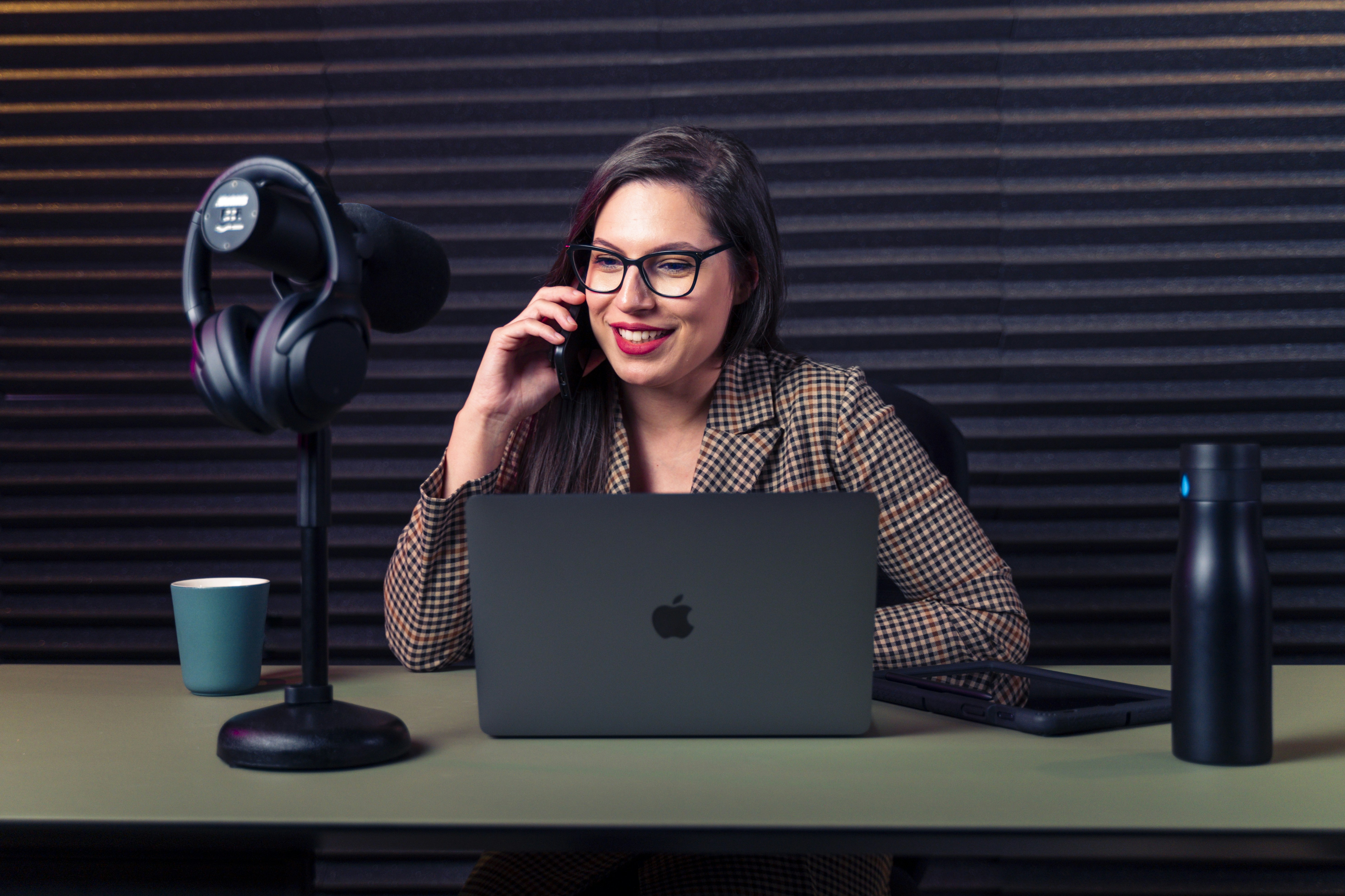 corporate finance professional reviewing spreadsheets on laptop while using desk microphone