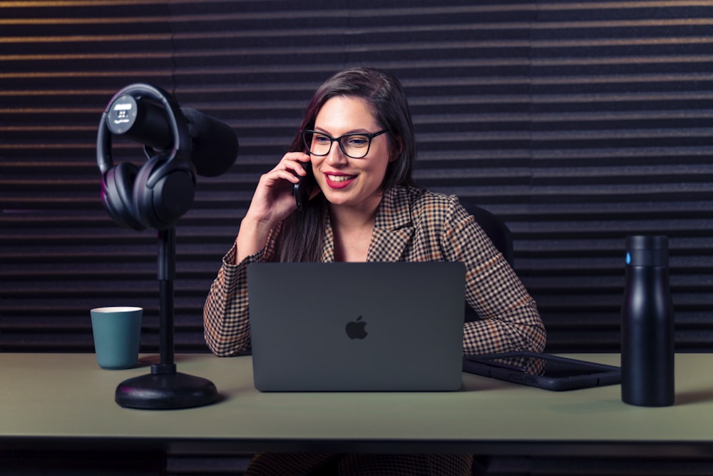 a woman sitting at a desk with a laptop and microphone