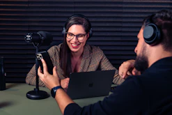 a man and woman with headsets on looking at a laptop