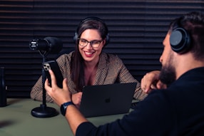 a man and woman with headsets on looking at a laptop