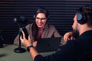 a man and woman with headsets on looking at a laptop