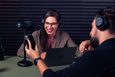 a man and woman with headsets on looking at a laptop