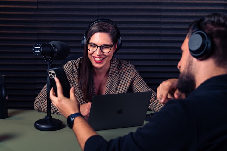 a man and woman with headsets on looking at a laptop