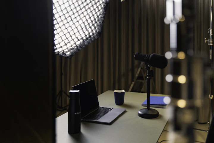 A laptop, microphone, and studio lights on a desk — a portable podcast rig like the one used to record curators on location