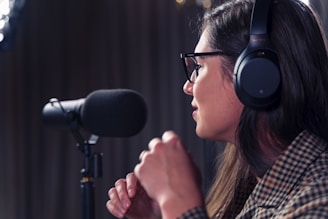 A woman wearing headphones and speaking into a mic.