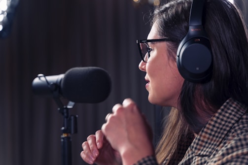 A woman wearing headphones and speaking into a mic.