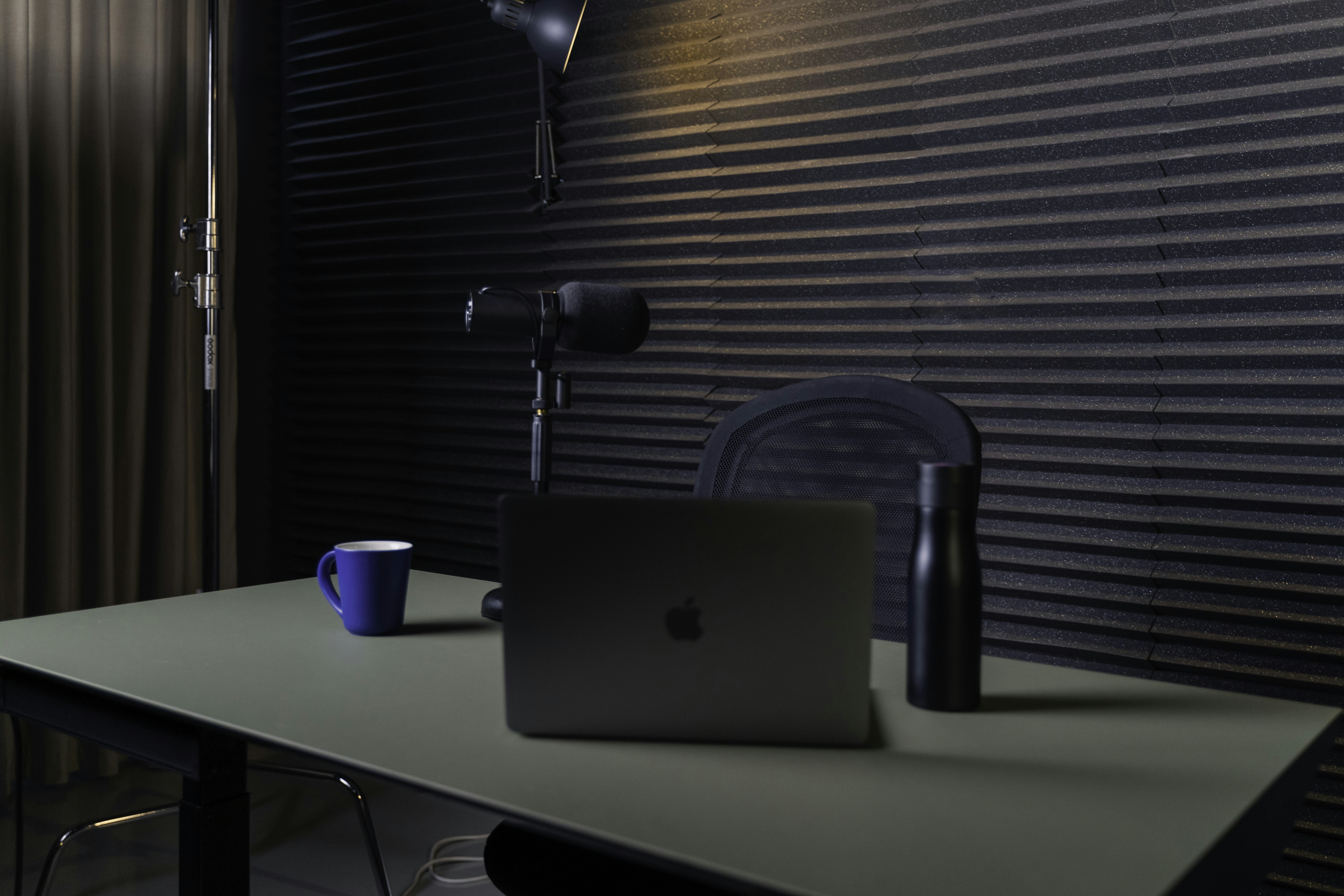Person using voice AI tools with a microphone and headphones in a bright home office. Technology-focused, modern decor, natural light.