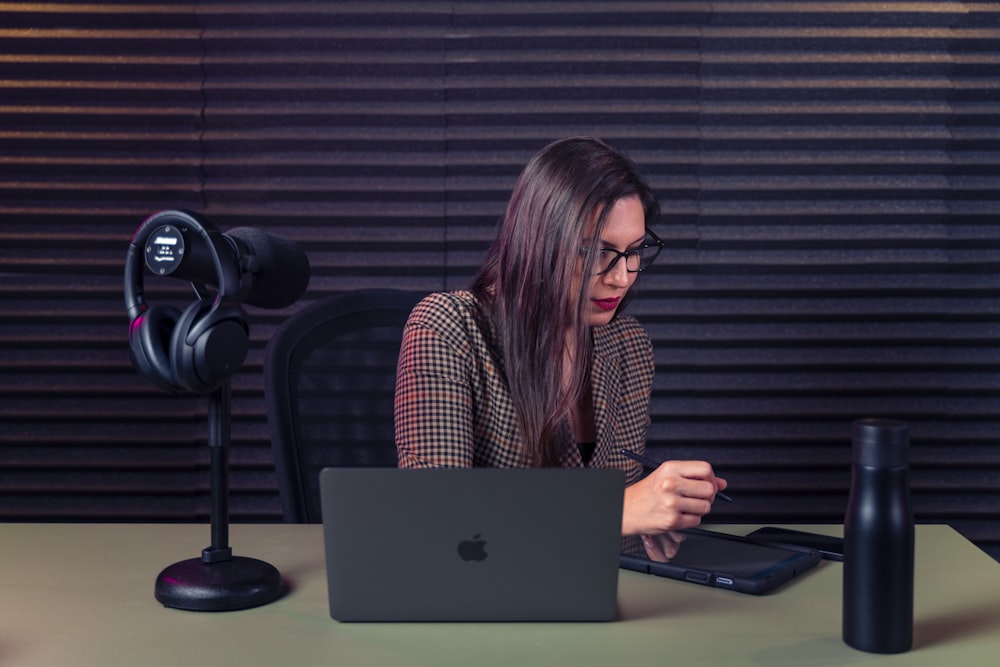 a woman sitting at a desk with a laptop and a microphone