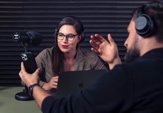 a man and woman with headsets on looking at a laptop
