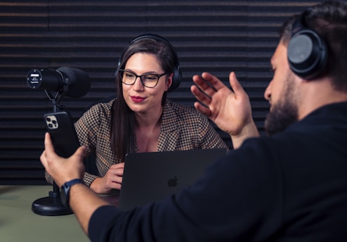 a man and woman with headsets on looking at a laptop