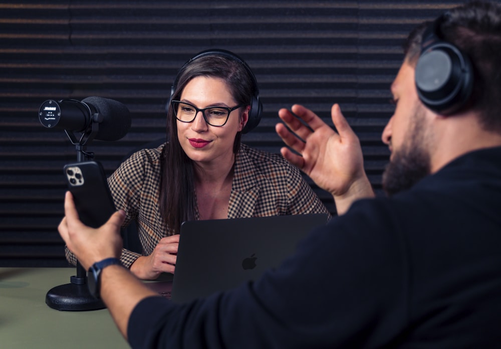 a man and woman with headsets on looking at a laptop