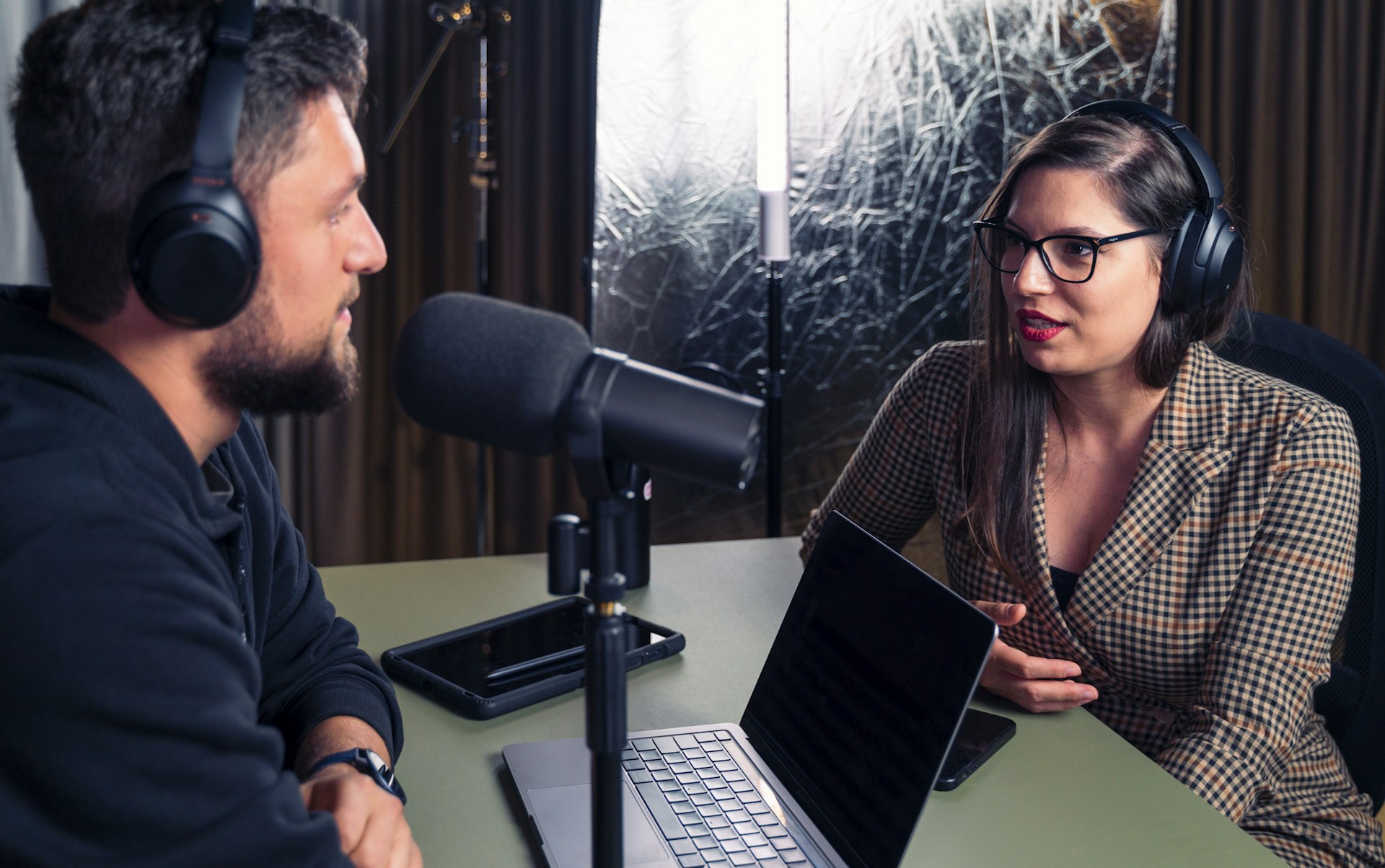 a man and a woman wearing headphones and looking at a laptop