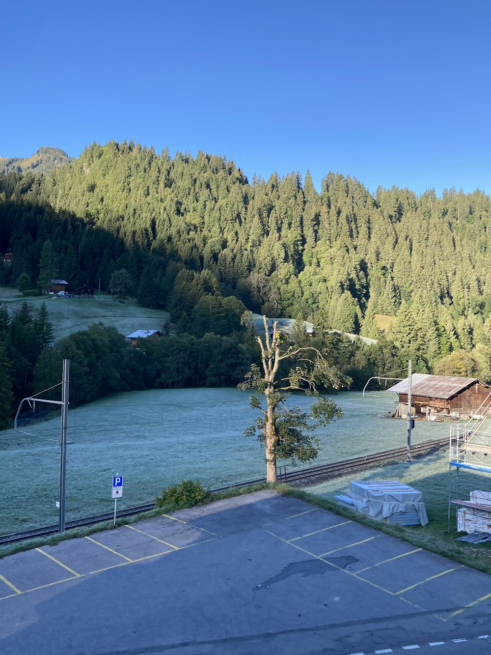 a pool next to a hill with trees and a building