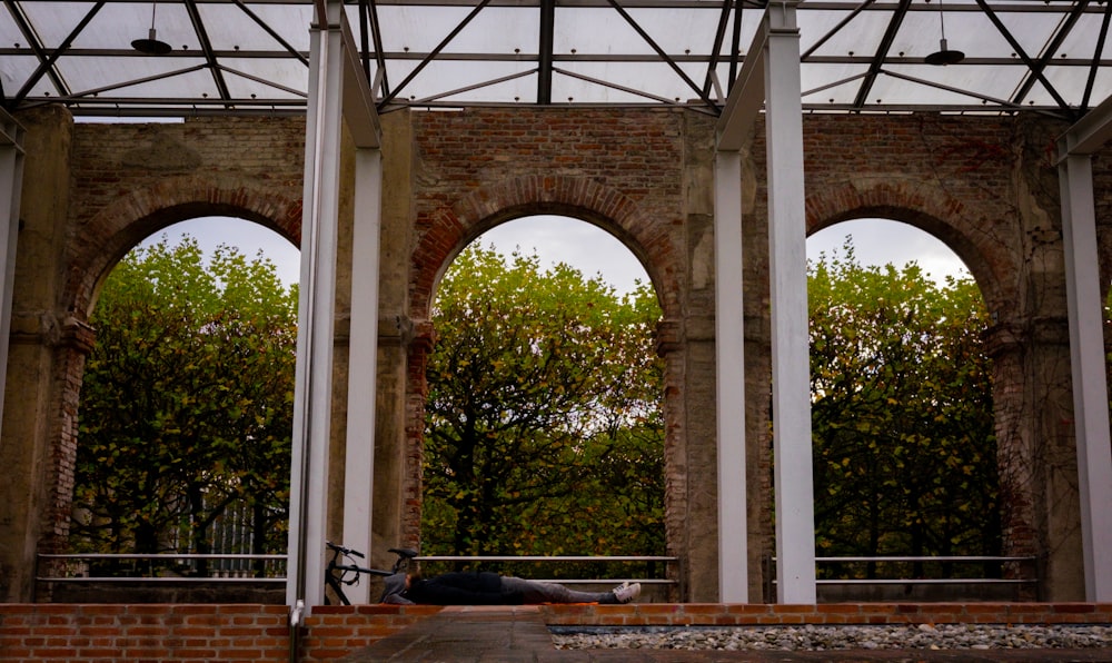 a person lying on the ground under a roof with trees in the background